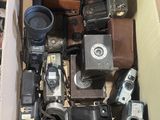 une boîte en carton remplie de vieux appareils photo et d'autres objets