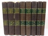 six old books are lined up in a row on a white surface