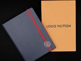 un carnet Louis Vuitton avec une bande rouge sur la couverture