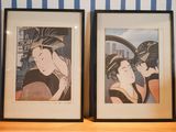 two framed prints of a woman in a kimono sitting on a shelf