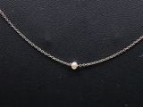 a silver necklace with a pearl on a black background