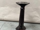 a black candle holder sitting on the floor next to a white wall