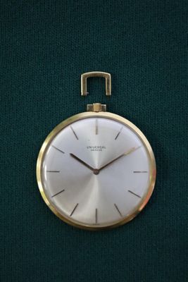 une horloge dorée accrochée à un tissu vert