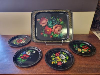 four plates with flowers painted on them sitting on a table