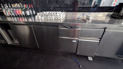 un plan de travail en acier inoxydable sur lequel sont posées plusieurs bouteilles