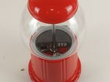 a red and clear gum ball machine on a white surface