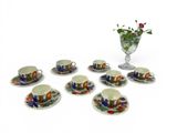 six cups and saucers with a vase of flowers in the background