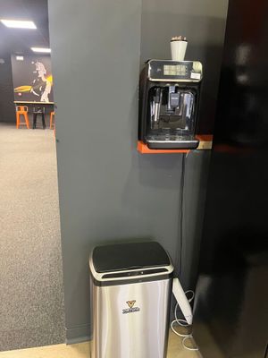 une cafetière et une poubelle dans un coin de la pièce