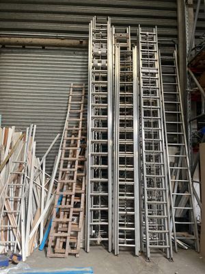 de nombreuses échelles métalliques empilées les unes sur les autres devant une porte de garage