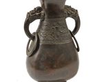 un vase en bronze posé sur une surface blanche