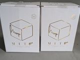 two white boxes with gold foil on them sitting next to each other