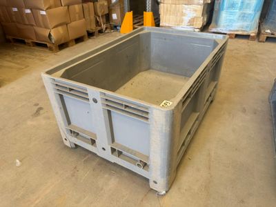 un grand conteneur métallique posé à même le sol dans un entrepôt