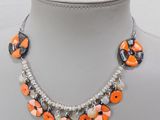 necklace with orange, black, and white beads on a white mannequin