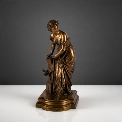 une statue antique en bronze représentant une femme tenant un panier de fleurs