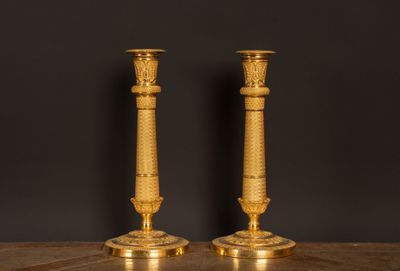 une paire de bougeoirs anciens en laiton posés sur une table en marbre