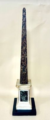 a stone obelisk with a marble base on a stand