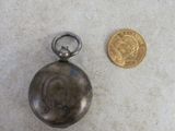 a small silver pocket watch next to a gold coin