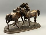 une statue en bronze représentant trois chevaux au galop sur une colline