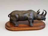 statue d'un rhinocéros posée sur un socle en bois, sur fond blanc