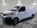 Une camionnette blanche est garée dans une pièce au sol carrelé en damier.