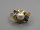 a close up of a pearl and diamond ring on a table