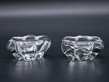 pair of clear glass candlestick holders on a black surface