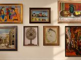 many paintings hanging on the wall in this room
