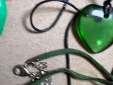 a green heart shaped glass pendant on a green cord