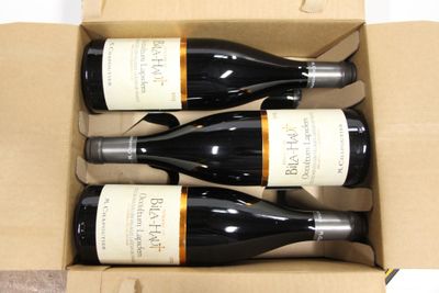 three bottles of wine are in a cardboard box on a table