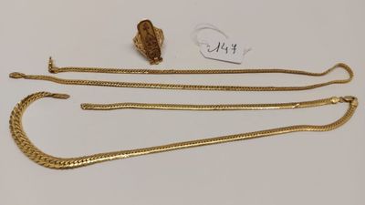 un collier en or et une chaîne en or posés sur une surface blanche