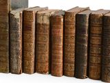 several old books are lined up in a row on a white surface