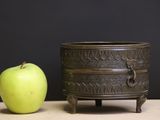 a green apple sitting next to a small metal pot