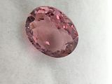 a pink oval shaped diamond on a white surface