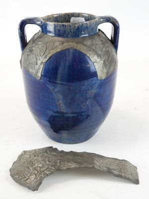 un vase bleu et un morceau de métal posés sur une surface blanche