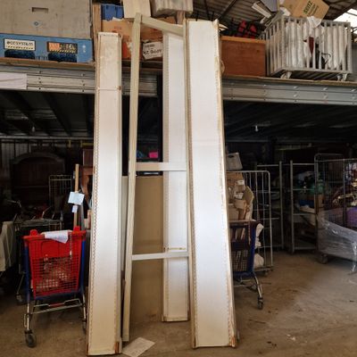 a pile of old doors in a warehouse with a shopping cart in the foreground