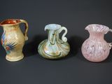 three different colored vases sitting next to each other on a black surface
