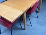 a wooden table with pink chairs and a black backpack