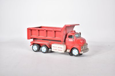 un camion jouet rouge posé sur une surface blanche