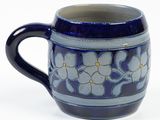 a blue mug with white flowers on it on a white surface