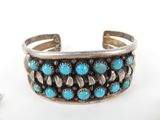a close up of a silver cuff with turquoise stones on it