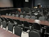 tables and chairs in a conference room with a projector screen in the background