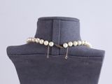 a white pearl choke with a gold chain on a mannequin