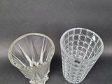 two clear glass vases on a table with a black background