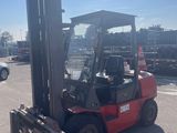 a red forklift truck parked in a parking lot