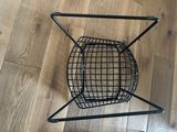 a black wire basket that is on a wooden floor