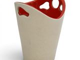 a red and white vase with a hole in it