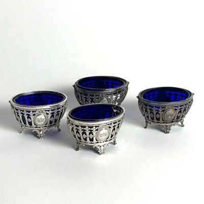 three silver and blue glass bowls sitting on top of a white surface