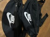 deux sacs banane Nike noirs posés sur un parquet