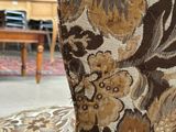 an upholstered chair in a living room with a table and chairs in the background