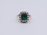 a close up of a ring with pearls and a green stone